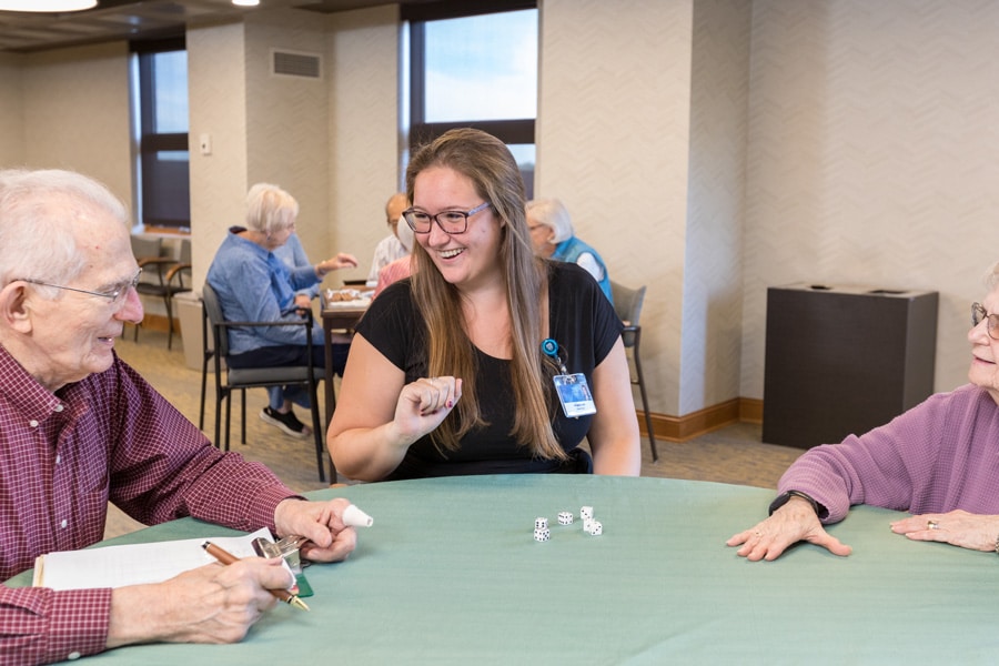 Female Employee Smiling While Playing Dice With Residents Female Employee Smiling While Playing Dice With Residents