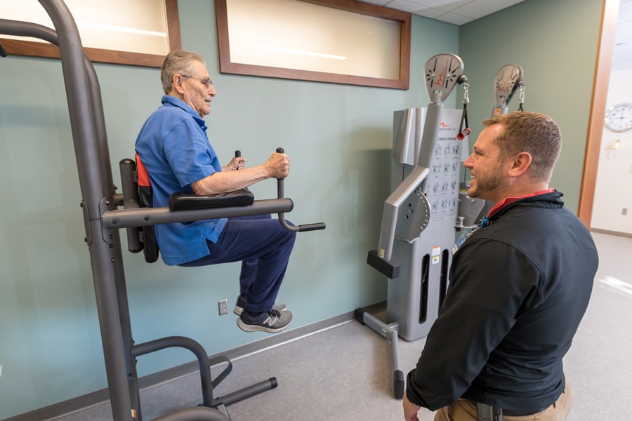 Fitness Center Employee Working With Resident Using Equipment Fitness Center Employee Working With Resident Using Equipment