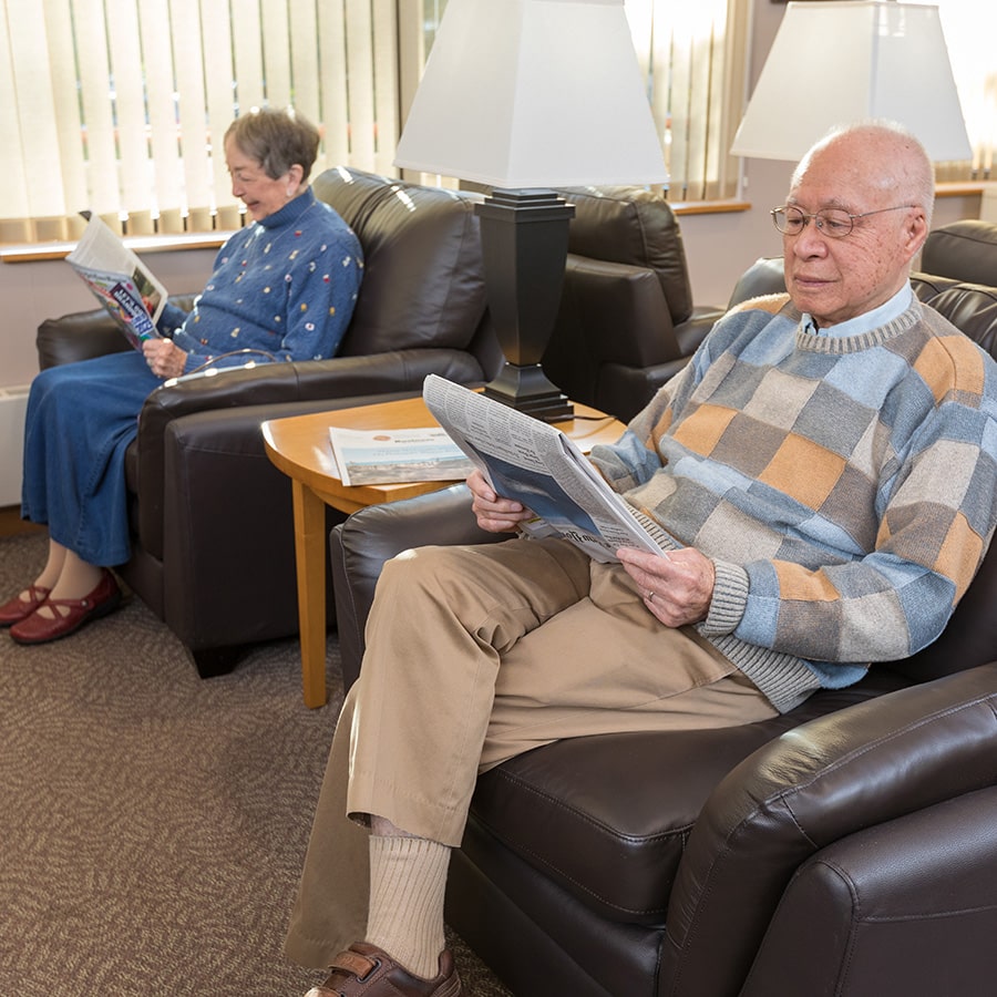 Man And Woman Reading While Sitting In Comfy Recliners Man And Woman Reading While Sitting In Comfy Recliners