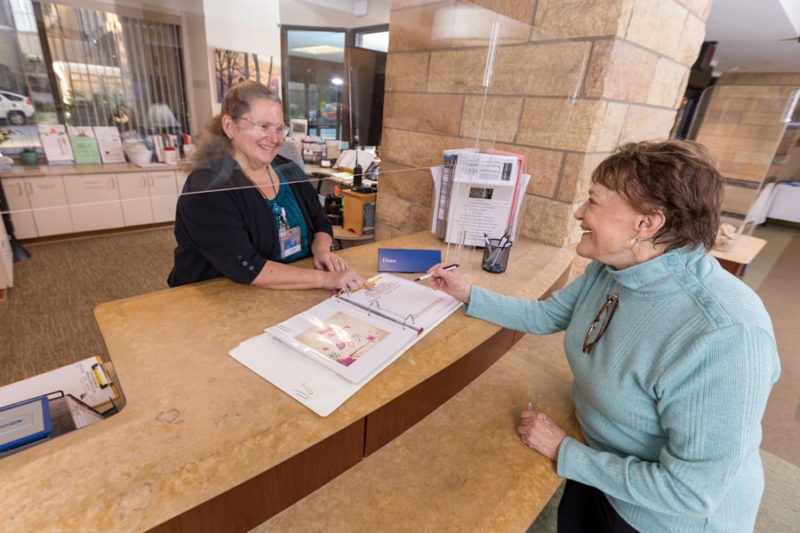 Woman Working Behind Desk Interacting With Resident Woman Working Behind Desk Interacting With Resident
