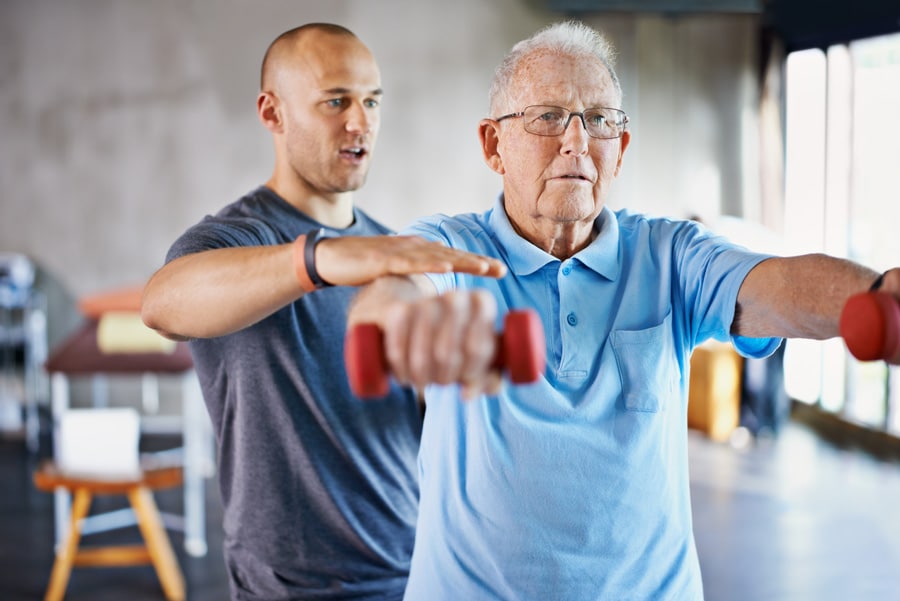 Physical Therapist Working With Elderly Patient Using Weights Physical Therapist Working With Elderly Patient Using Weights